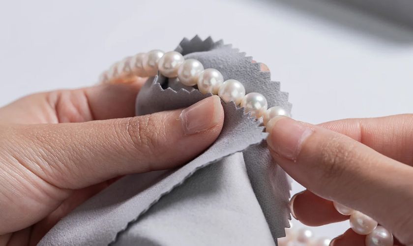 Dùng khăn mềm ẩm lau nhẹ nhàng bề mặt ngọc trai và vàng là cách bảo quản nhẫn vàng đính ngọc trai 18K đúng cách